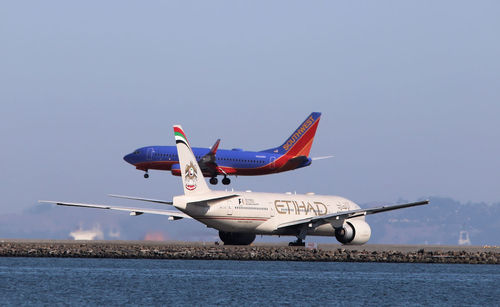 Airplane flying over water against clear sky