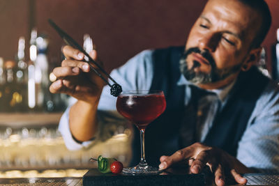 Midsection of man holding wine glass on table