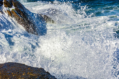 Wave impact against the rocks with sea water splashing in the air