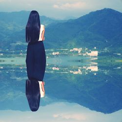 Rear view of woman standing by lake against mountains