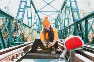 Portrait of young woman sitting on bridge