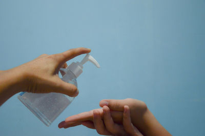 Midsection of people holding hands against blue background