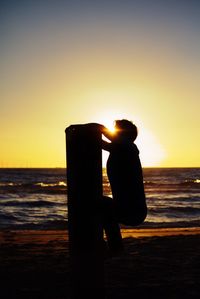 Close-up of person photographing sea at sunset
