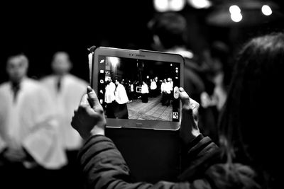 Woman photographing men from digital tablet at night