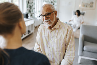 Retired senior man talking with female caregiver while sitting at nursing home