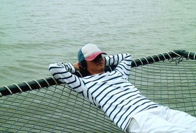 Young man relaxing on net over sea