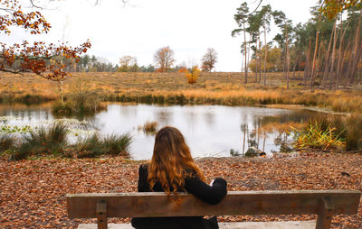 Young woman with long hair sitting on a branch admiring the nature