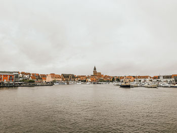 Buildings at waterfront against cloudy sky