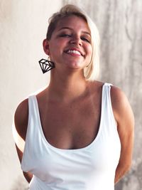 Portrait of smiling young woman standing against wall