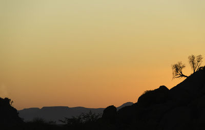 Scenic view of silhouette mountains against orange sky