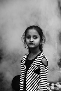 Portrait of young woman standing against blurred background