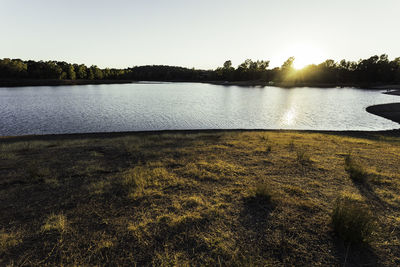 Scenic view of lake against clear sky during sunset