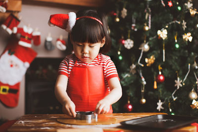 Girl preparing food on table against christmas tree