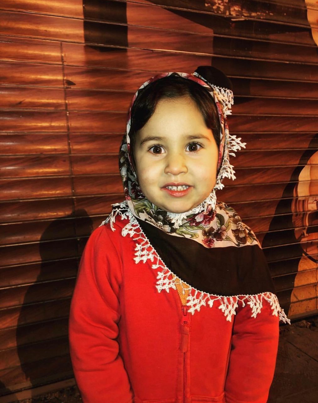 PORTRAIT OF SMILING GIRL STANDING AGAINST RED BRICK WALL