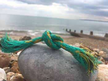 Close-up of rope tied up on beach against sky