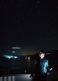 Rear view of man standing against sky at night