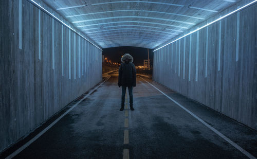 Rear view of man walking in illuminated tunnel