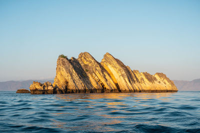 Scenic view of rock formation in sea against clear sky