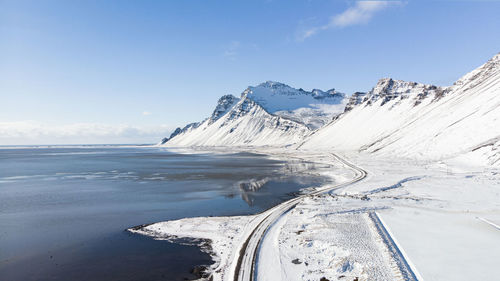 Scenic view of snowcapped mountains by sea against sky