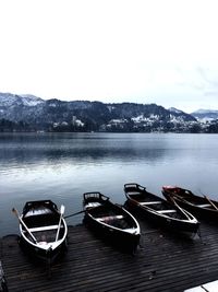 Boats moored on lake against sky