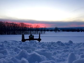 Cannon on snowy field against sky during sunset