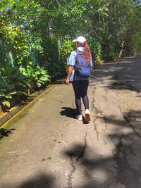 Full length rear view of woman walking on footpath