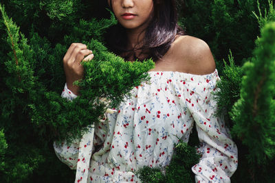 Woman in traditional clothing amidst plants against trees