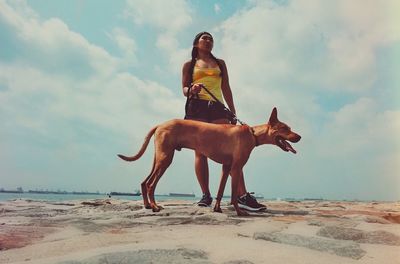 Full length of woman sitting on beach against sky