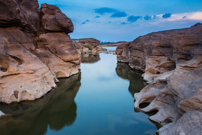 Rock formations in water against sky