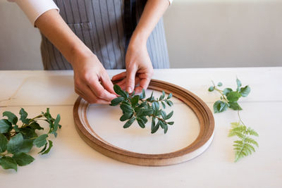 Woman puts branches of plants into frame for making botanical bas-relief. female hands for working 