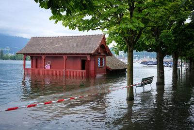 Wooden posts in lake by building against sky