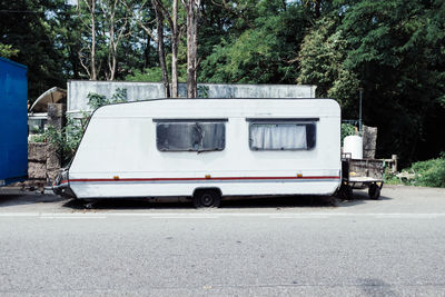 Camper trailer on road against trees