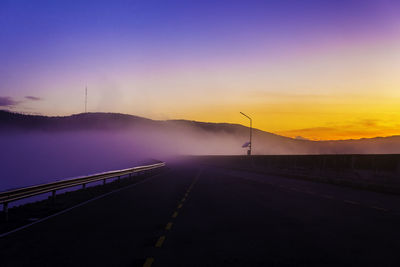 Road by against mountains and sky during sunset