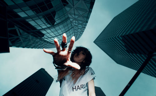 Low angle portrait of woman standing by modern buildings in city