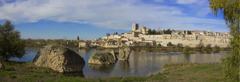 Buildings by river against sky in city