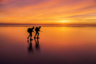 People ice-skating at sunset, vanern, sweden