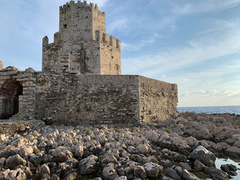 Historic building by rocks against sky