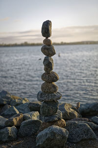 Stack of pebbles in sea during sunset