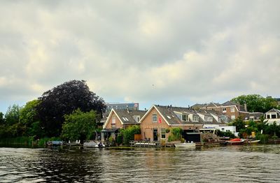 Houses by river and buildings against sky