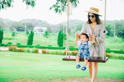 Mother holding son sitting on swing at park