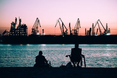 Silhouette of pier in sea at sunset