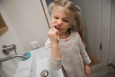 Girl brushing teeth in bathroom at home