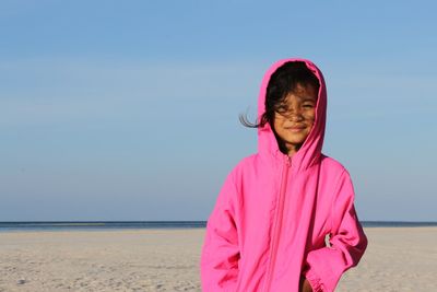 Portrait of young woman standing at beach against clear sky
