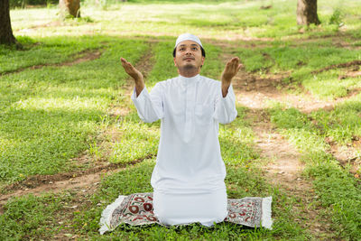 Muslim man praying to allah god of islam  on green meadow.