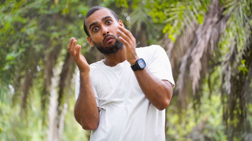 Young man looking away while standing in forest