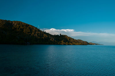 Scenic view of sea and mountains against blue sky