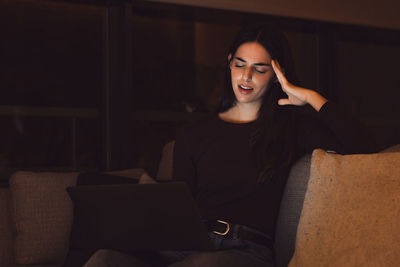 Portrait of young woman sitting on sofa at home