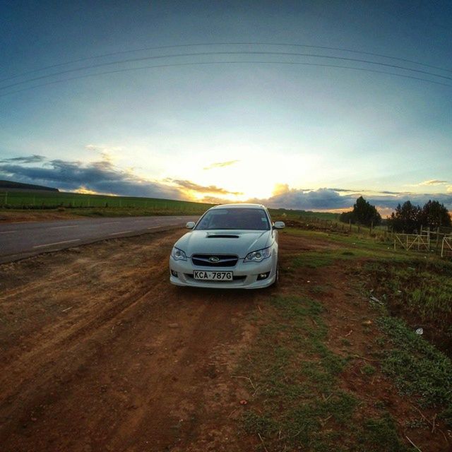 transportation, land vehicle, car, landscape, mode of transport, sky, road, field, sun, tranquil scene, sunlight, sunset, travel, nature, scenics, tranquility, cloud, cloud - sky, beauty in nature, on the move