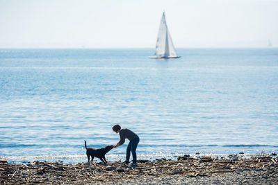 Scenic view woman and a dog playing on beach