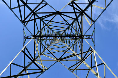 Low angle view of electricity pylon against clear blue sky